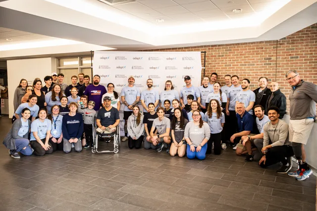 Clinic participants, coaches and volunteers in matching T-shirts posing for a group photo, one in a wheelchair