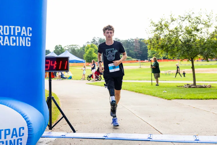 A runner with a prosthetic running blade alongside a young girl